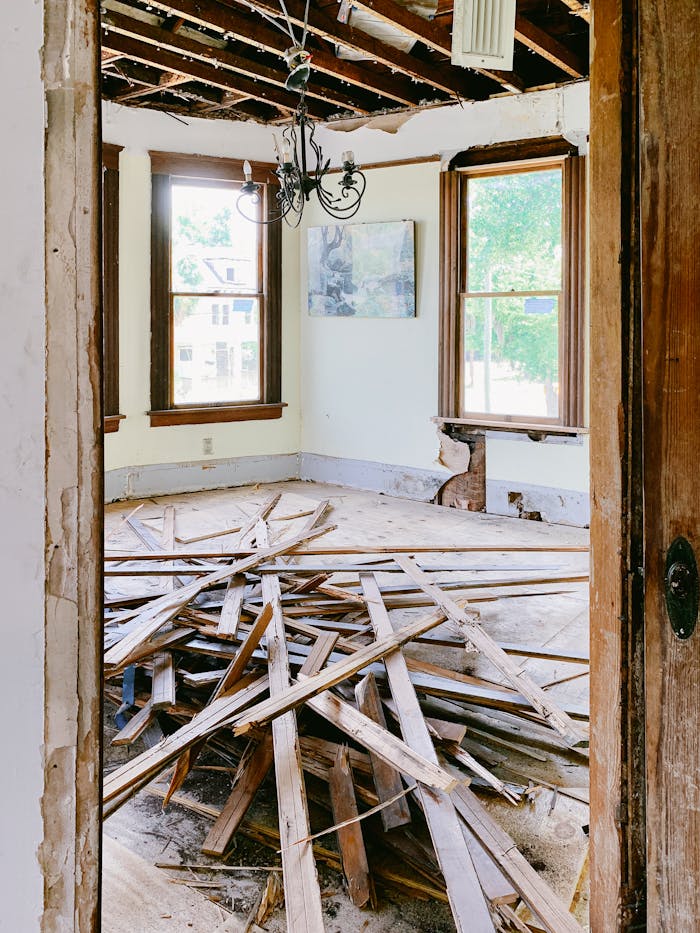 pexels-photo-4756488 Interior room under renovation with exposed beams and planks piled on the floor.